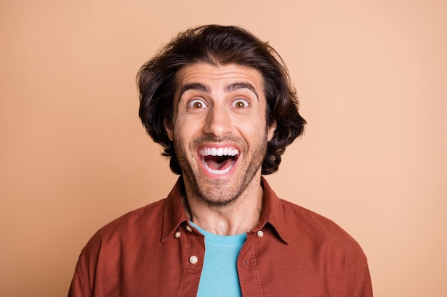 Photo portrait of excited guy with open mouth isolated on pastel beige colored background