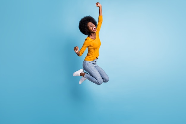 Photo portrait full size of active brunette girl jumping up celebrating isolated on pastel blue colored background