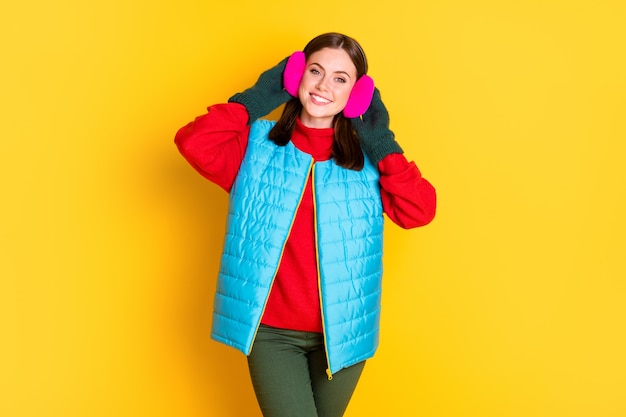 Photo of positive cheerful charming girl enjoy winter cold weather weekend touch earmuffs enjoy wear season outfit isolated over vivid color background