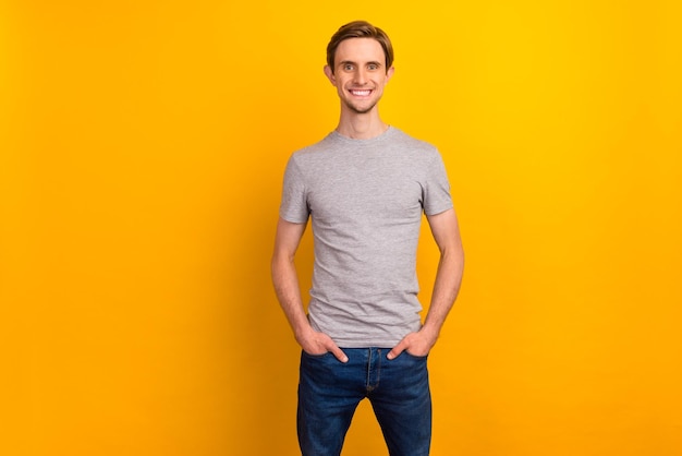 Photo of positive good looking man hands pockets jeans smiling isolated on bright color background