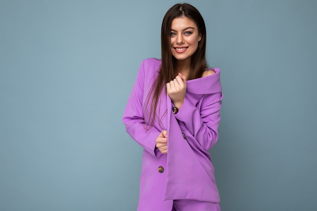 Photo of positive young business long hair brunette woman wearing purple suit isolated on blue background. Copy space.