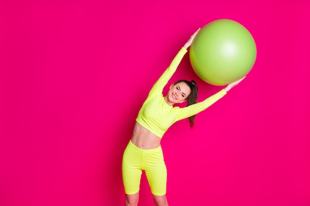 Photo of positive young sportswoman bend fit ball aside stretching back isolated over pink shine color background