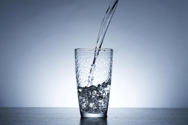 Photo of pouring water into a glass of water