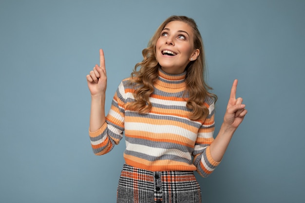 Photo of pretty astonished young woman pointing fingers up at copyspace presenting incredible ads