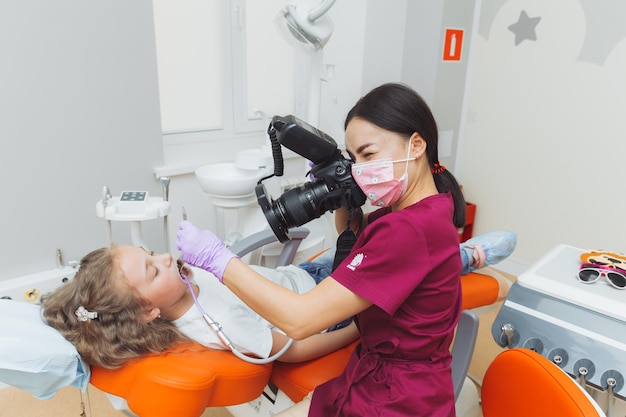 Photo protocol in dentistry the doctor photographs the girl's teeth examines the girl's mouth children's dentistry