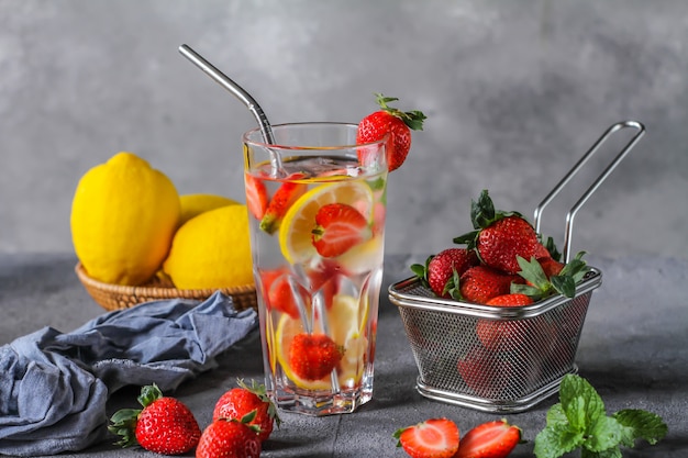 Photo of refreshing summer iced cold drink. Strawberry infused waters. Mineral water with fresh strawberries lemon with a grey background. Detox water with strawberry lemon. Copy space.