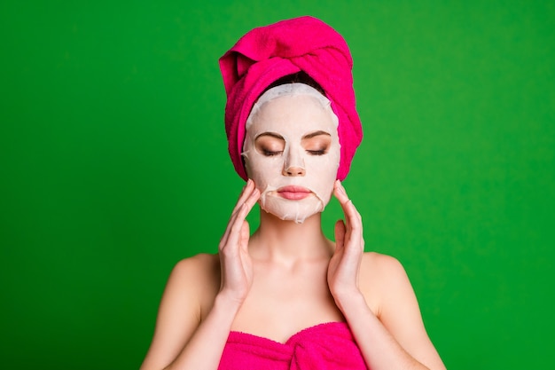 Photo of relaxed lady apply collagen mask on face eyes closed touch cheeks towels body head isolated green color background