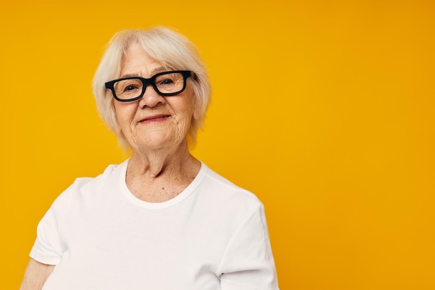 Photo of retired old lady in casual tshirt and glasses yellow background