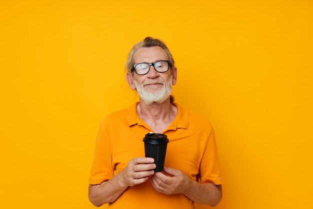 Photo of retired old man in a yellow Tshirt a glass with a drink isolated background