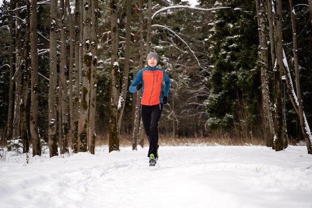 Photo of running athlete among trees in winter forest