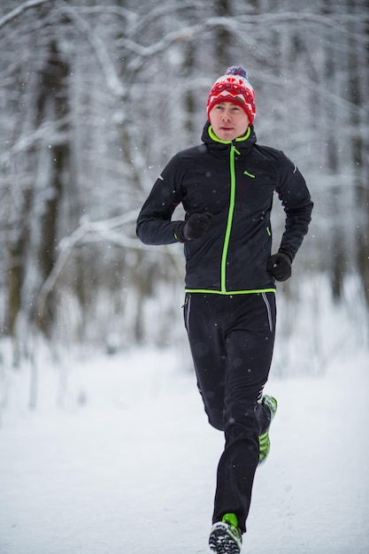 Photo of running athlete among trees in winter forest