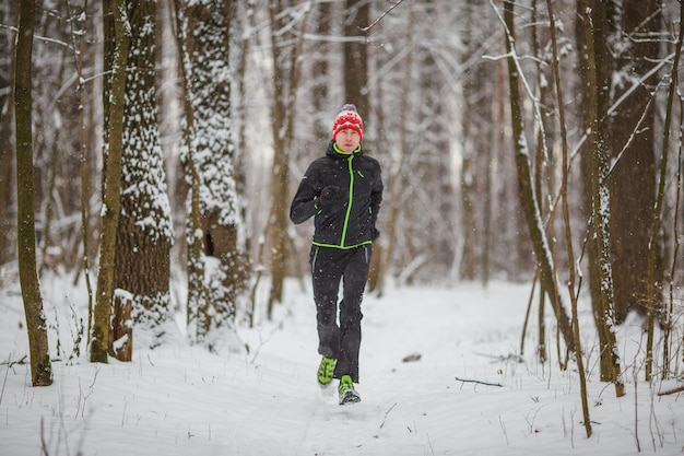 Photo of running athlete among trees in winter forest