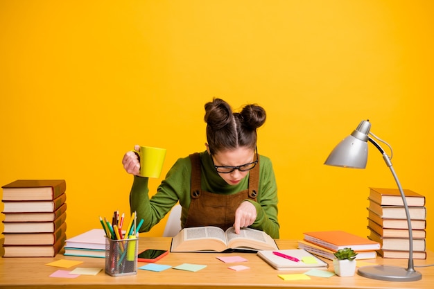 Photo of school girl sit desk hold coffee cup read textbook on yellow background