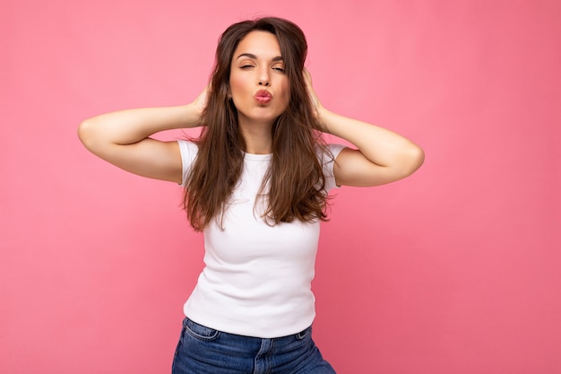 Photo shot of cute nice charming gorgeous attractive pretty youngster happy woman wearing white t-shirt for mockup isolated over colorful background with copy space and giving kiss.