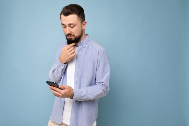 Photo shot of handsome concentrated good looking young man wearing casual stylish outfit poising