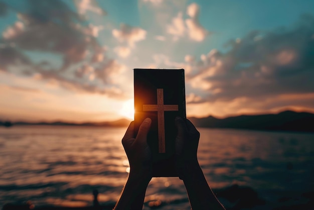 Photo photo silhouette of human hand holding bible and cross the background is the sunrise