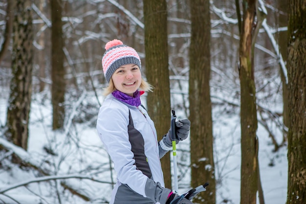 Photo of smiling woman with skis in winter forest