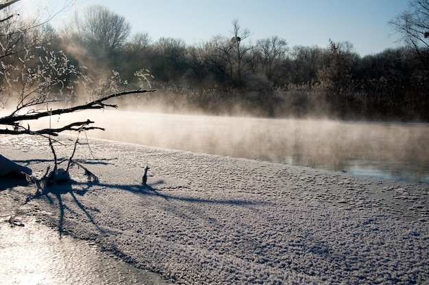 Photo the snowcovered river did not freeze in winterThe river flows in winter Snow on the branches of trees Reflection of snow in the river Huge snowdrifts lie on the Bank of the stream