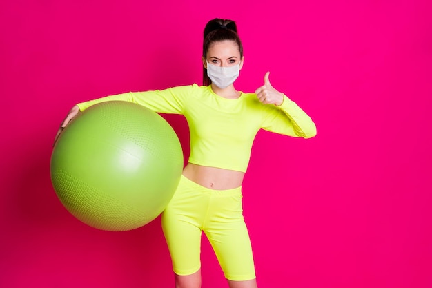 Photo of sportswoman hold fitball show thumb-up symbol wear respiratory isolated pink bright color background