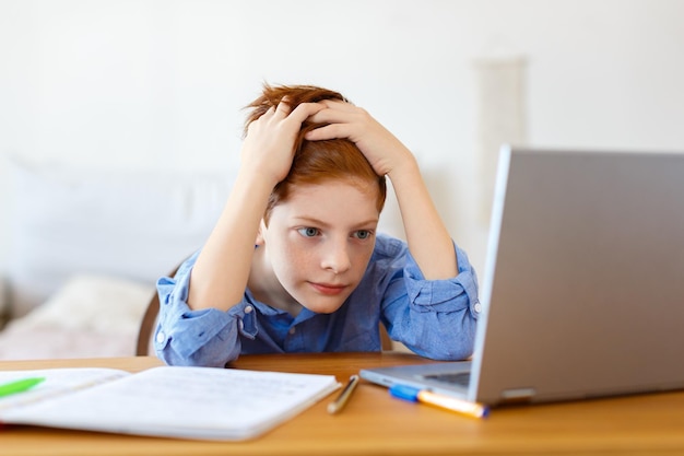 Photo of a student during an online lesson he sits ind listens to a boring lesson topic