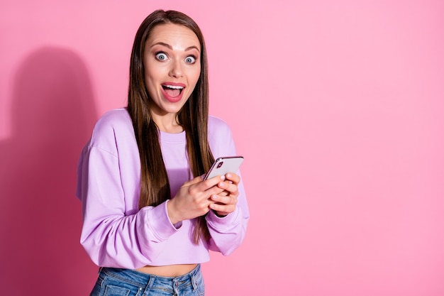 Photo of surprised crazy girl addicted blogger use cellphone impressed social media news comment wear lilac style stylish trendy pullover denim jeans isolated pastel color background