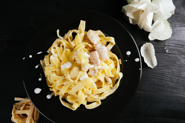 A photo of a tasty meal of spaghettis on a wooden dark table