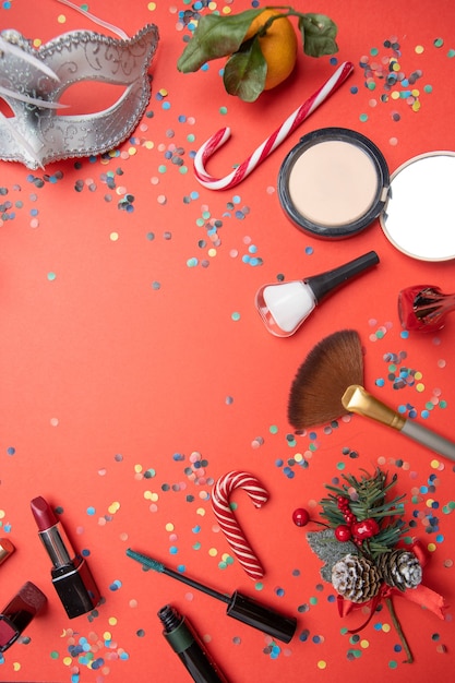 Photo on top of brushes, feather mask, tangerine, sugar cane on empty red table