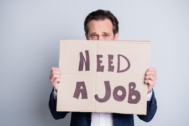 Photo of unhappy sad stressed worker aged mature guy upset financial crisis lost work carton placard hide half facial expression search work moody wear blue suit isolated grey background