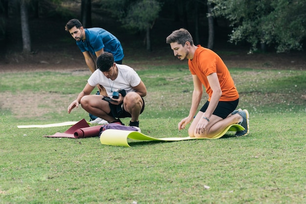 Photo with copy space of three men preparing yoga mats for a yoga session in the forest