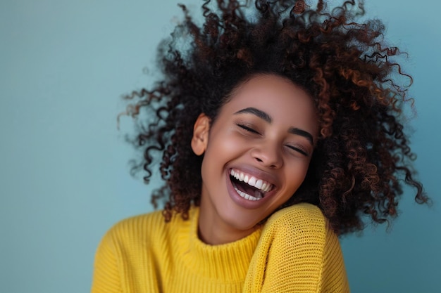 Photo of a woman with curly hair laughing and wearing yellow sweater isolated on solid color backgro