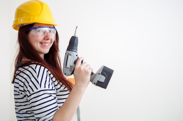 Photo of woman in yellow helmet with drill in hand apartment