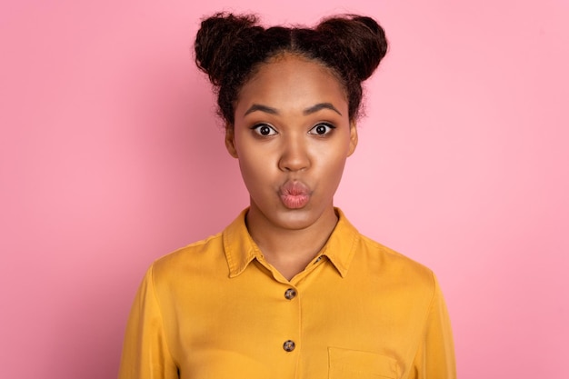 Photo of young african lady pouted lips send air kiss romantic valentine day isolated over pink color background