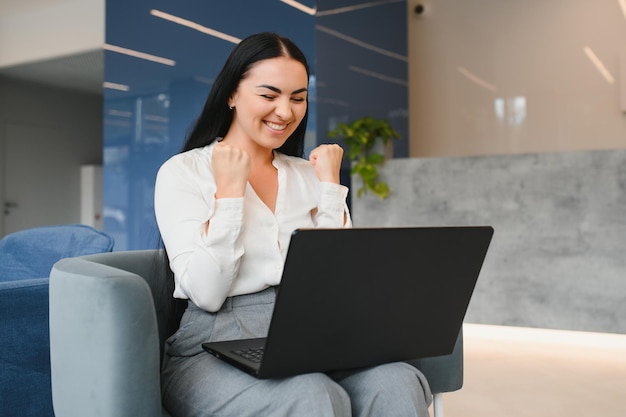 Photo of young attractive woman happy positive smile rejoice victory fists hands achievement look laptop