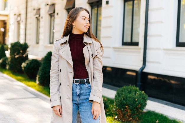 Photo of a young beautiful lady looking and smiling away near a cafe in a city