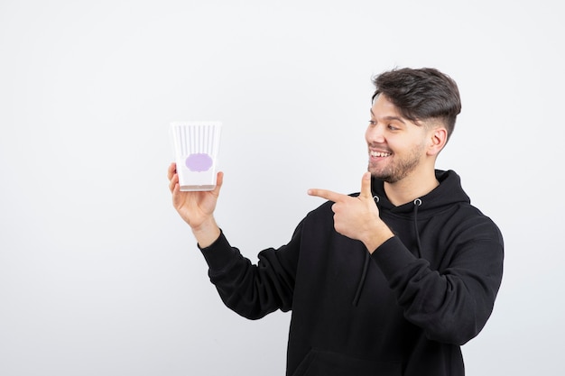 Photo of young beautiful man watching television series and holding popcorn bucket 