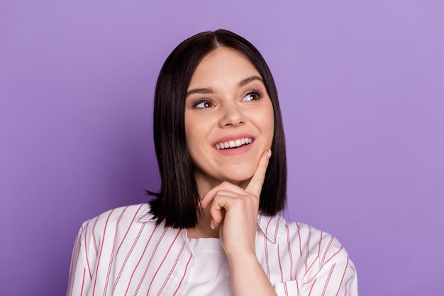 Photo of young cheerful lady finger touch chin dreamy curious look empty space isolated over violet color background