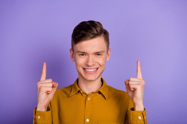 Photo of young cheerful man indicate fingers empty space discount proposition isolated over violet color background