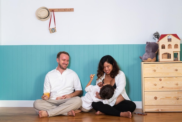 Photo of young cheerful positive smiling couple pregnant wife and husband with their son relaxing at home