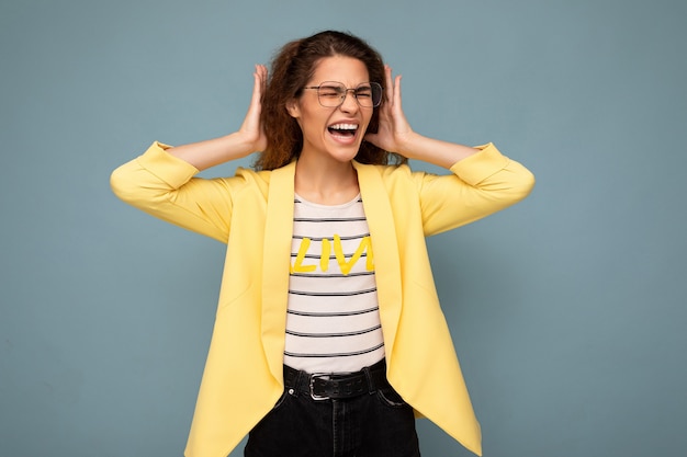 Photo of young emotional angry attractive brunette curly woman with sincere emotions wearing stylish