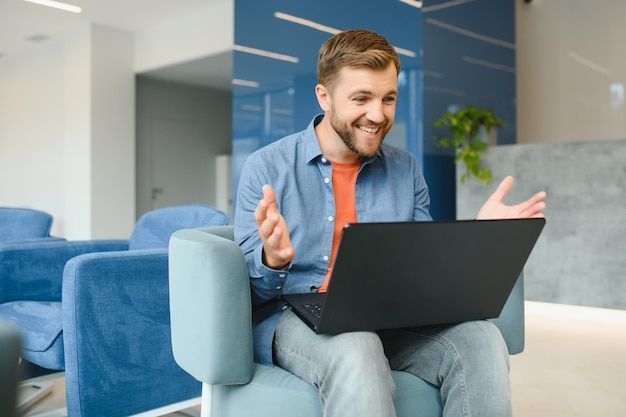 Photo of young excited man happy positive smile celebrate win victory success fists hands sit sofa home remote work