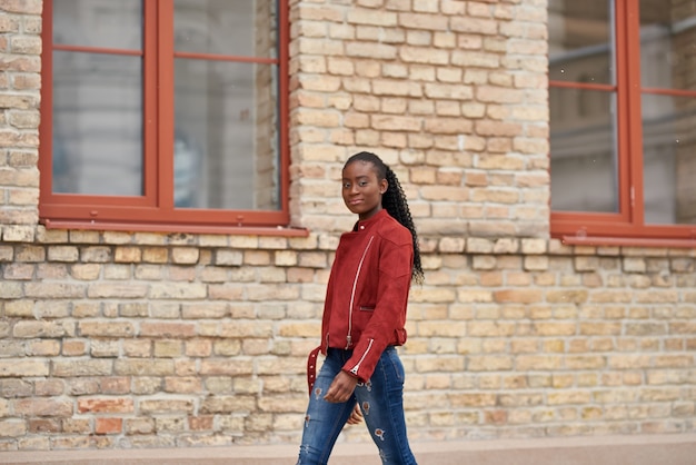 Photo of young fashionable afro woman with afro hairstyle walking on the city street