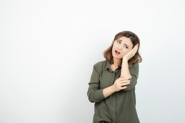 Photo of young girl having headache over white wall. High quality photo