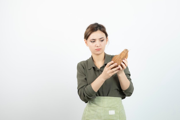 Photo of young girl looking at hairy coconut over white. High quality photo