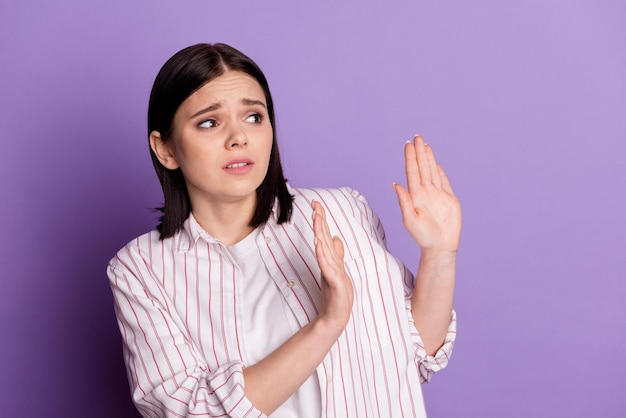 Photo of young girl scared worried anxious look empty space show hands decline sign isolated over violet color background