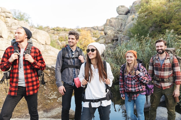 Photo of young group of friends outside in free alternative vacation camping over mountains walking.