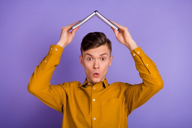 Photo of young guy hold book above head protection hone safety isolated over violet color background