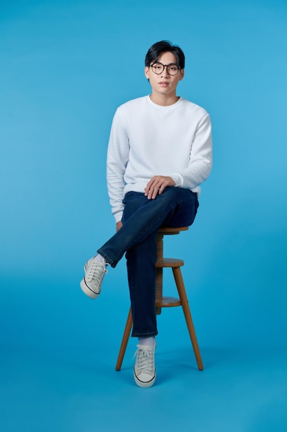 Photo of young guy smiling sitting chair empty space isolated blue color background