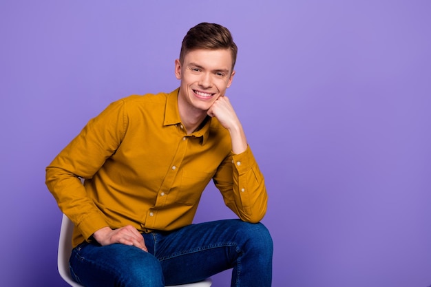 Photo of young handsome guy arm touch chin think dream confident sit chair isolated over violet color background