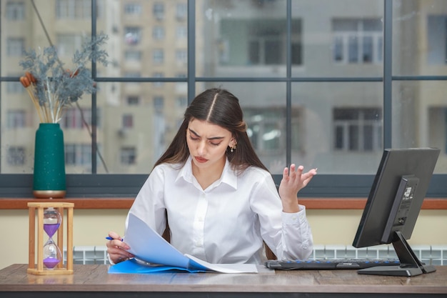 Photo of young lady holding notebook and reading her notes with anger