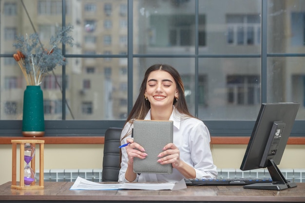 Photo of young lady holding notebook and smiling